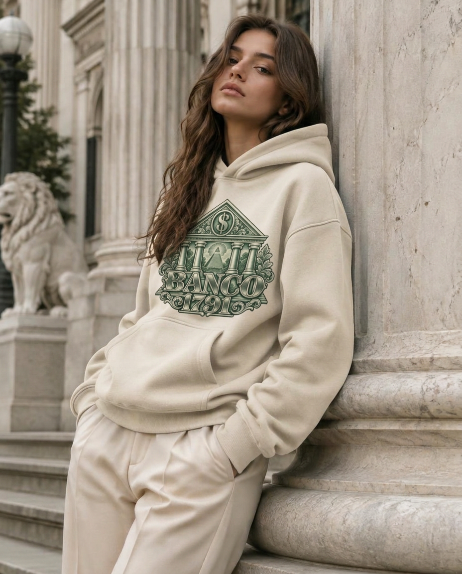 Model in a cream BANCO 1791 hoodie at a marble bank column